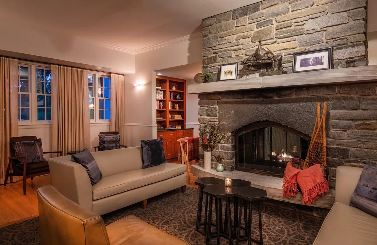 A warm, inviting living area featuring a decorative electric fireplace, a cozy seating arrangement, and a bookcase filled with books. The setting is perfect for relaxing by the fire or enjoying a quiet moment with a good read.