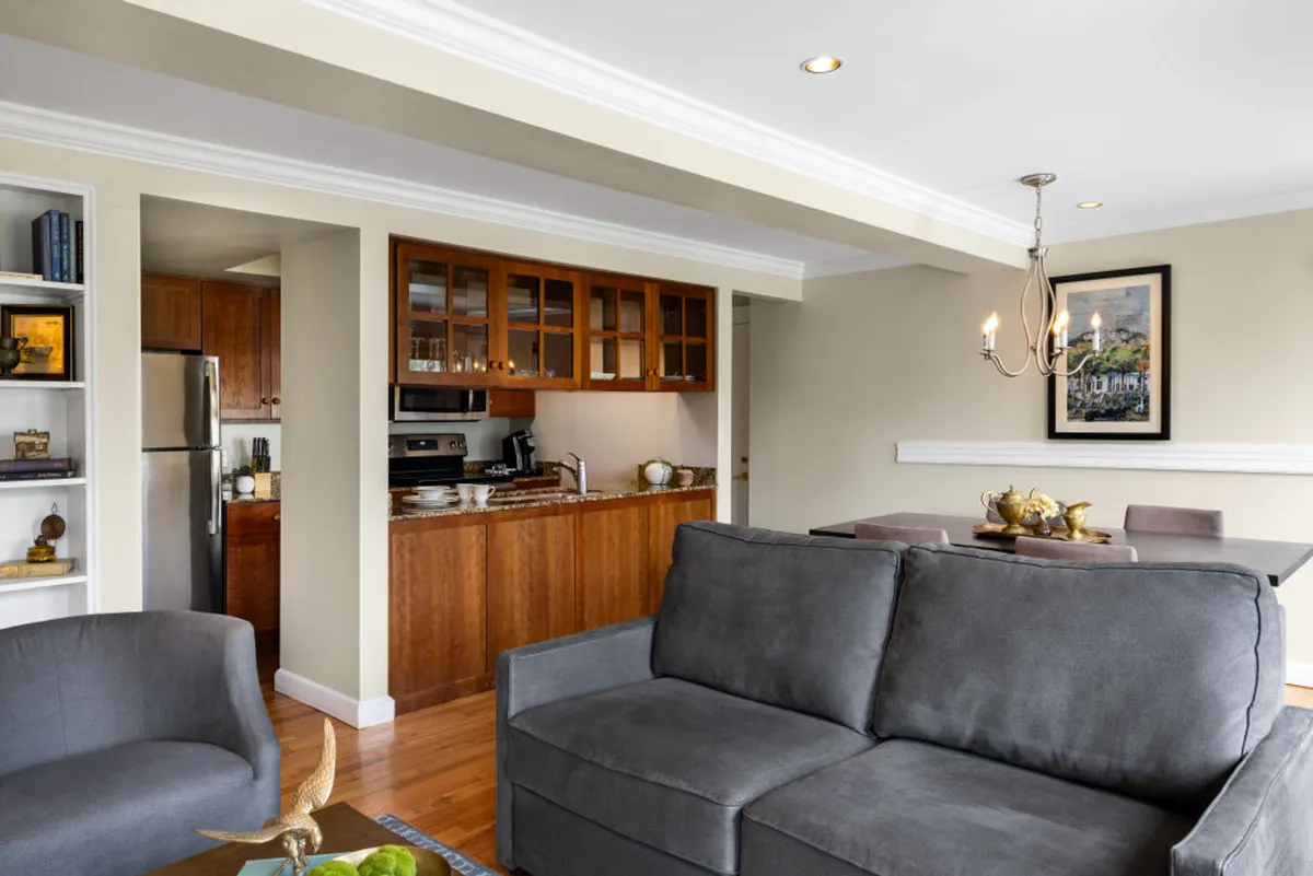 An open-plan living area with a comfortable sofa, a dining table set for meals, and a modern, fully equipped kitchen. Tasteful artwork and decor blend traditional and contemporary styles, capturing the suite's unique character and versatility for both relaxation and gatherings.